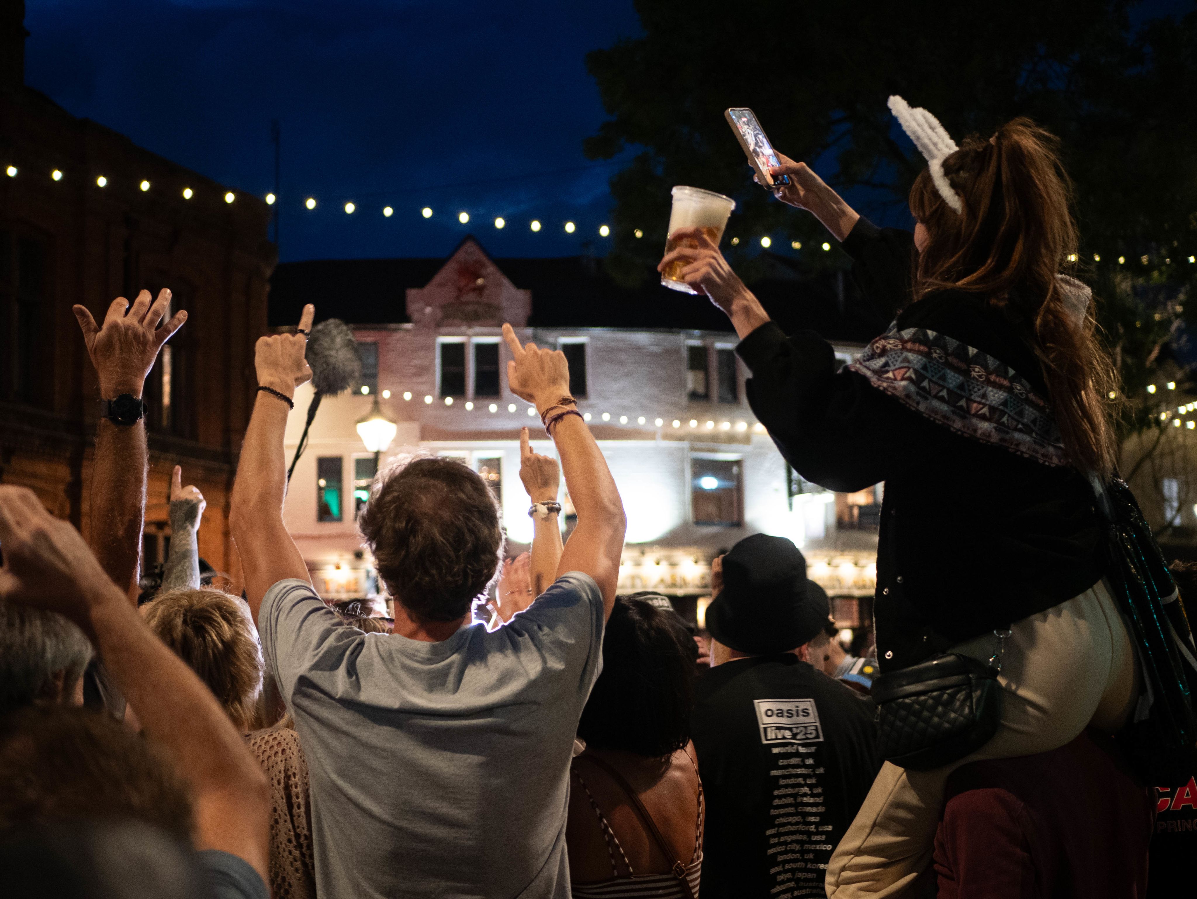 Crowd outside the City Arms pub with their hands in the air singing