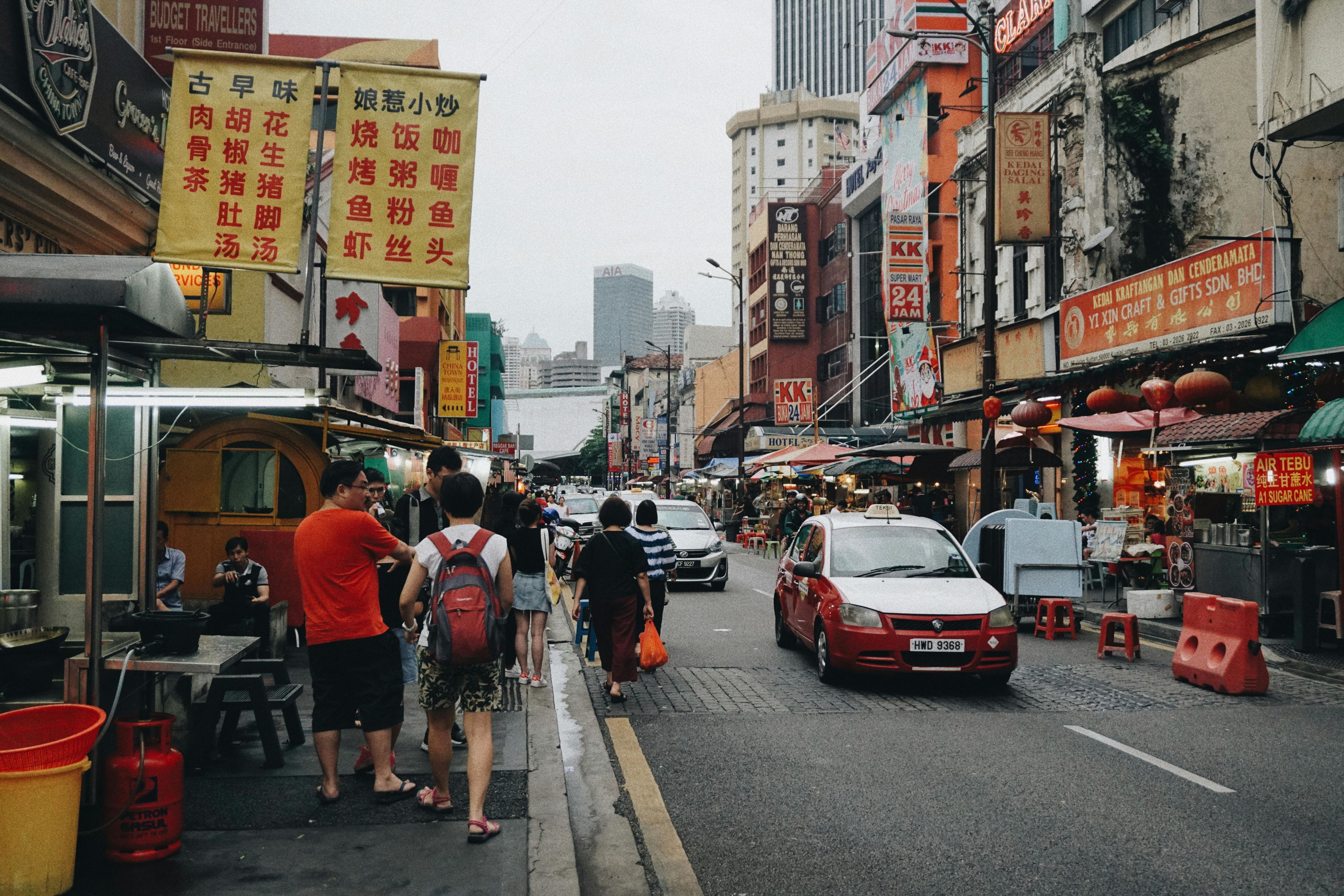 Vibrant street scene in Kuala Lumpur's Chinatown showcasing bustling activity and colorful signage.